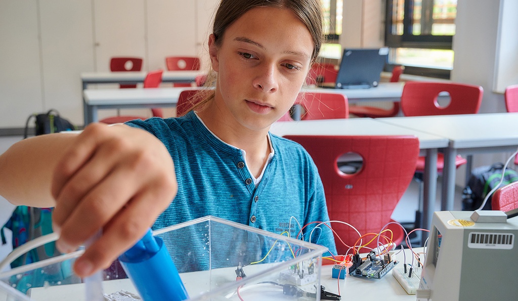 Junge sitzt am Tisch und experimentiert.