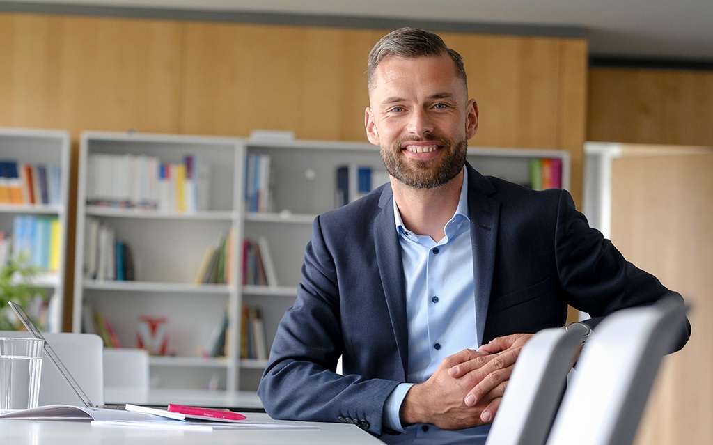 Jacob Chammon sitzt an einem Tisch. Vor ihm liegen Unterlagen.