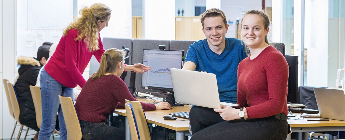 Teacher and students work on computers and laptops