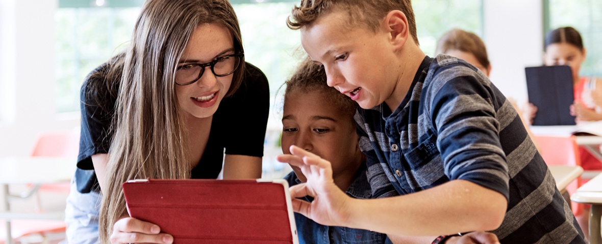 Lehrerin und Schüler schauen auf einen Tablet-PC