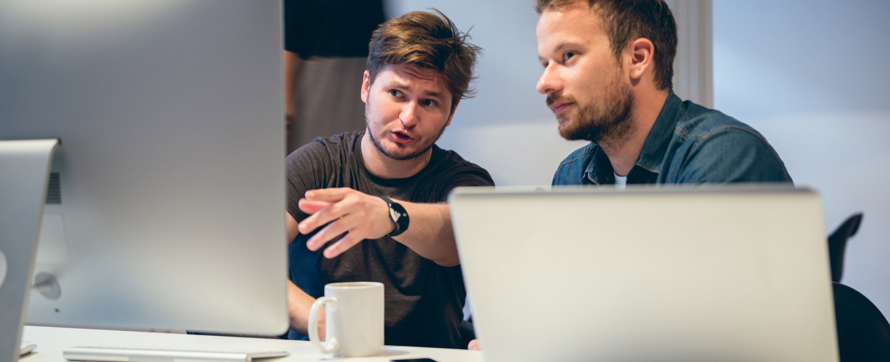 Two young researchers sit at the computer and discuss.