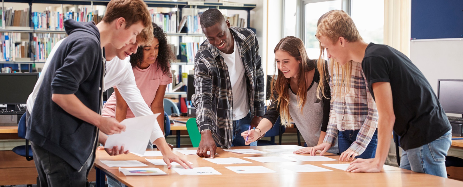 Lehrkraft und Schüler arbeiten an Computern und Laptops.