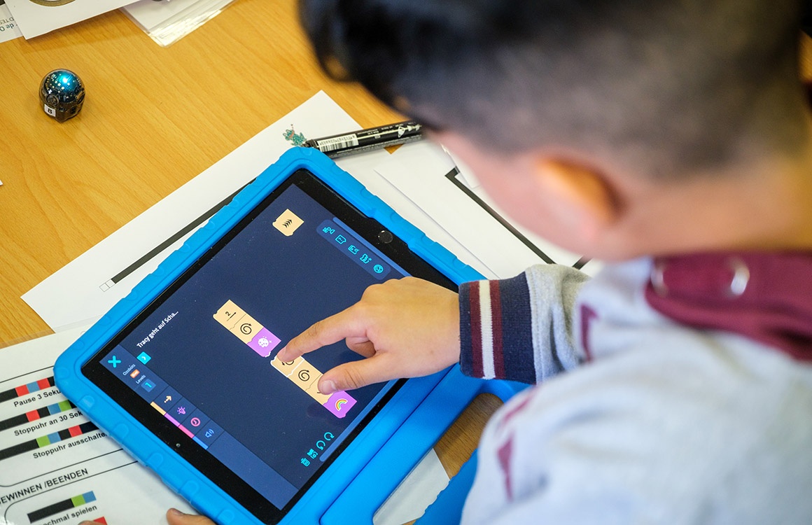 Junge programmiert Roboter auf Tablet.