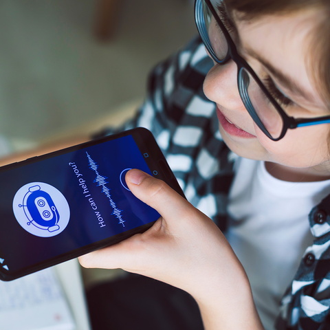 Junge hat ein Smartphone mit einer KI-Anwendung in der Hand.