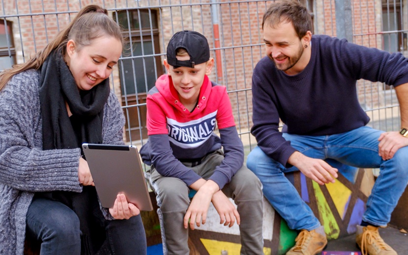 Pädagogen erklären einem Jugendlichen etwas auf dem Tablet-PC