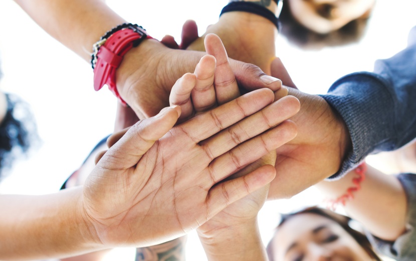 Menschen legen Hände aufeinander.