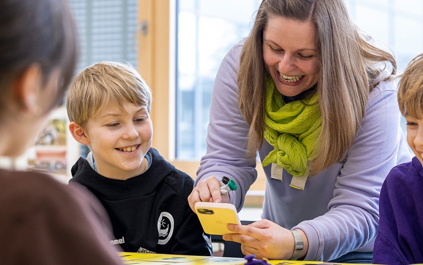 Schülerinnen und Schüler spielen gemeinsam mit Lehrkraft Moonshot.