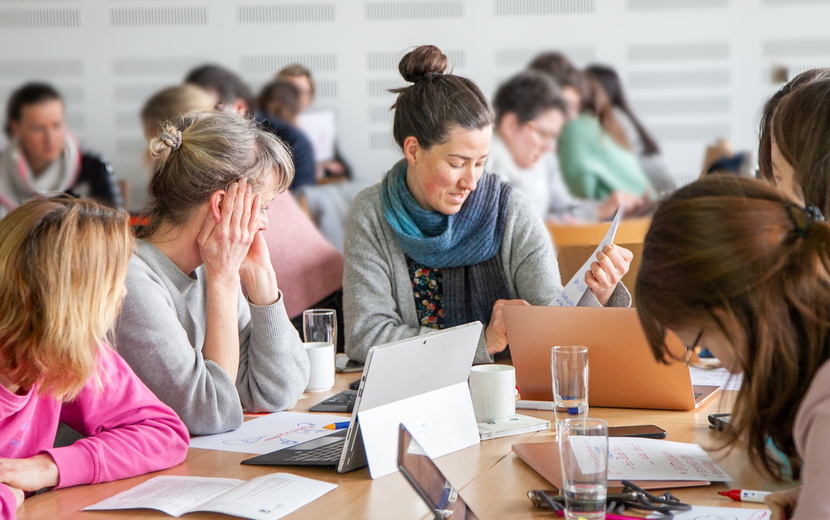 Menschen sitzen gemeinsam an einem großen Tisch und arbeiten gemeinsam.