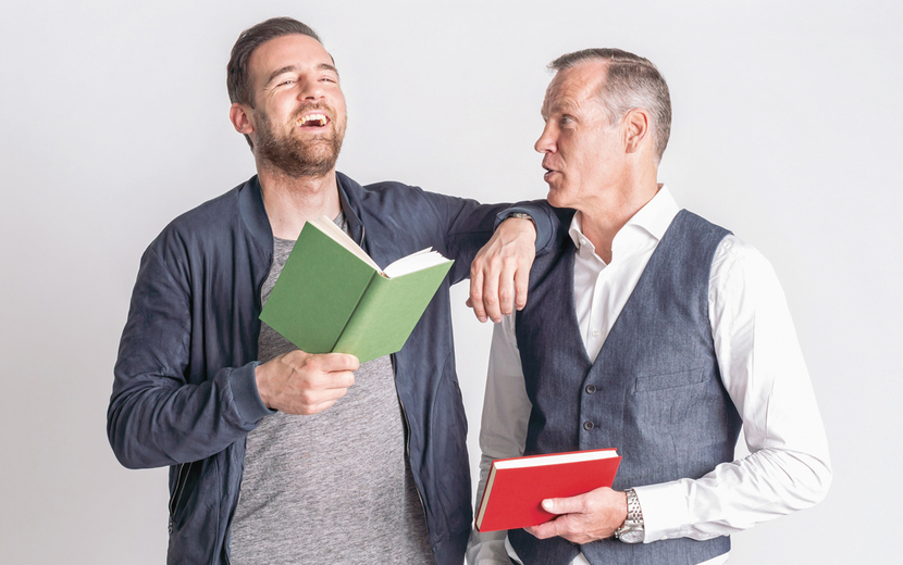 Christoph Metzelder und Henry Maske halten Bücher in der Hand und lachen