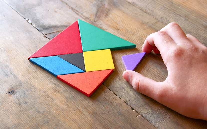 Eine Hand bewegt eines von mehreren Puzzelteilen