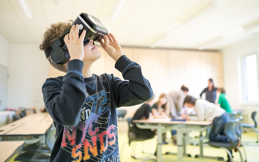 Das Bild zeigt einen Schüler mit VR-Brille im Klassenraum.