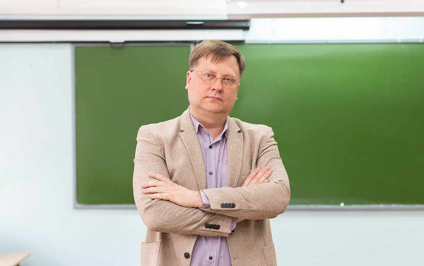 Schulleiter steht mit verschränkten Armen in Klassenzimmer.