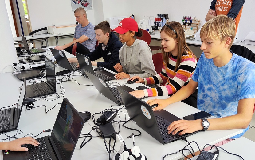 Jugendliche sitzen vor Laptops.