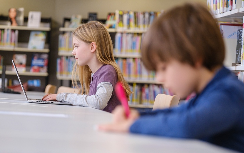 Kinder sitzen in Bibliothek.