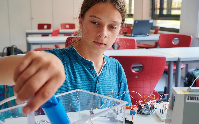 Junge sitzt am Tisch und experimentiert.