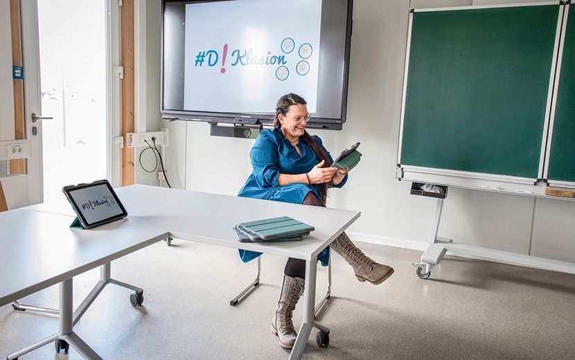 Lea Schulz sitzt mit einem Tablet im Klassenzimmer.