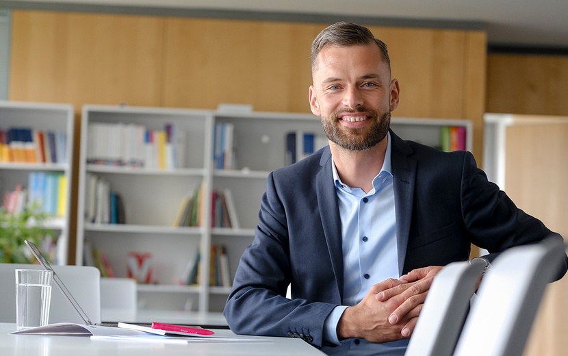 Jacob Chammon sitzt an einem Tisch. Vor ihm liegen Unterlagen.