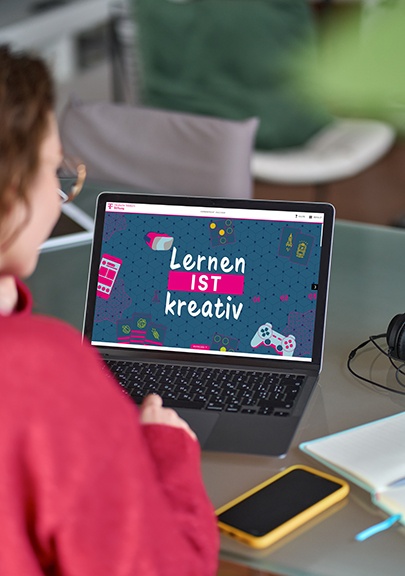 Junge Frau sitzt vor Laptop und schaut sich den Jahresbericht der Deutsche Telekom Stiftung an.