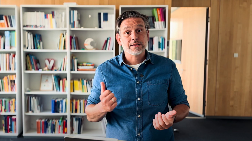 Projektleiter Benjamin Wockenfuß steht vor einem Bücherregal und schaut in die Kamera.