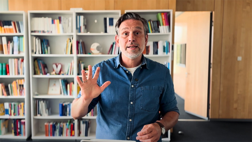 Projektleiter Benjamin Wockenfuß steht vor einem Bücherregal und schaut in die Kamera.